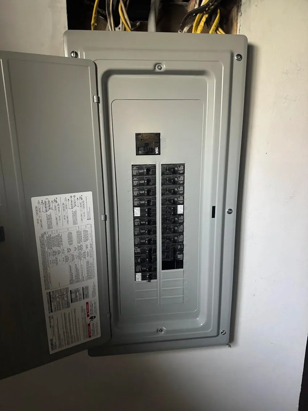 An open residential breaker panel with the circuit directory label on the inside of the door