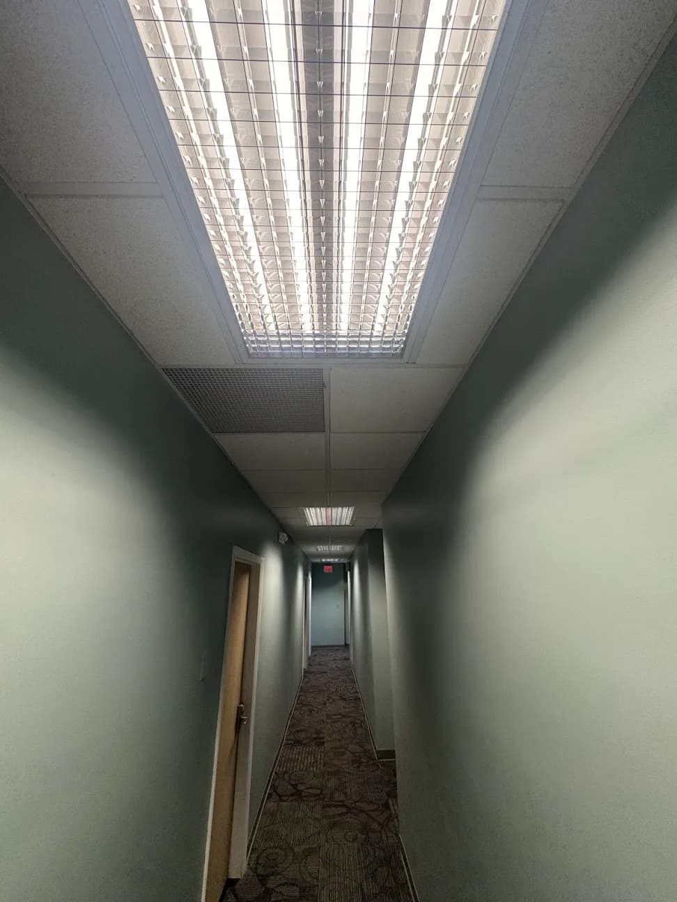 A corridor lit by a long recessed ceiling fixture