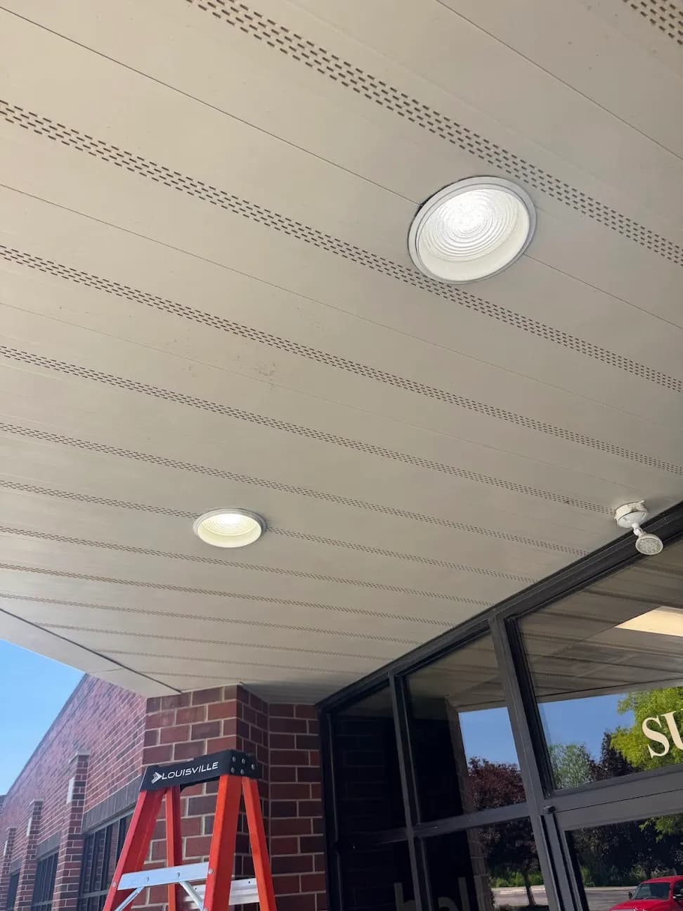 Recessed lights installed in the soffit above a brick building entrance