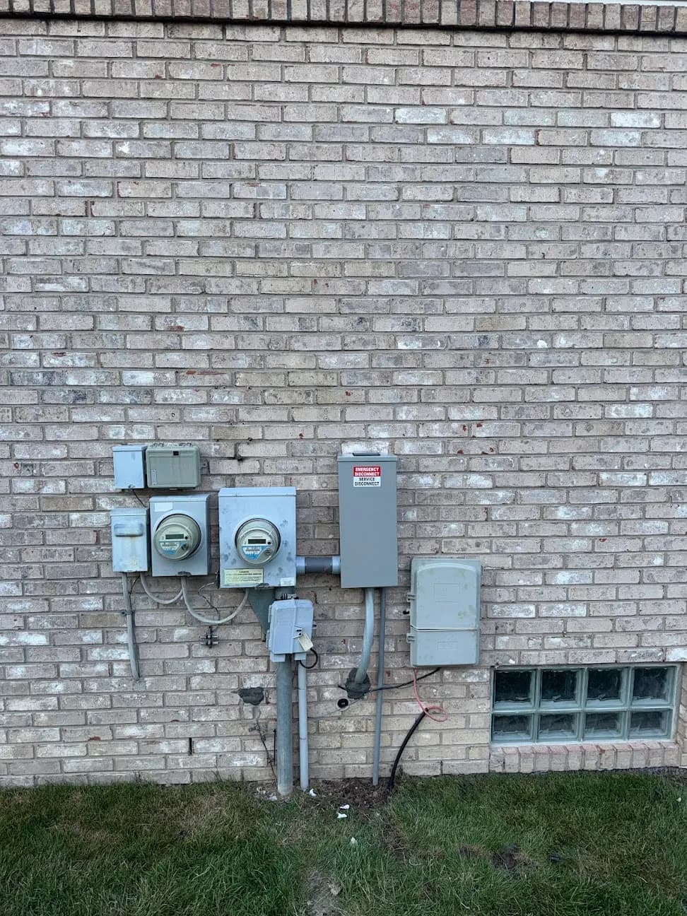 A bank of electrical meters and disconnects mounted on a brick exterior wall