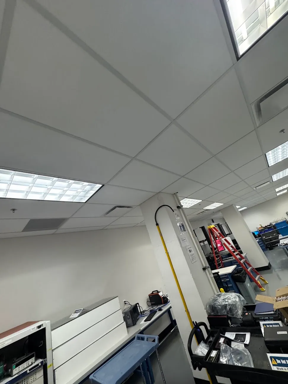 An office and shop interior with recessed ceiling light panels above workbenches