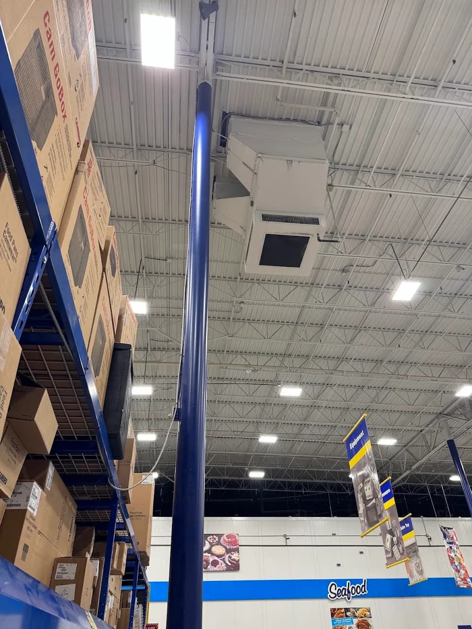 Ceiling lighting and conduit above a retail aisle stacked with product