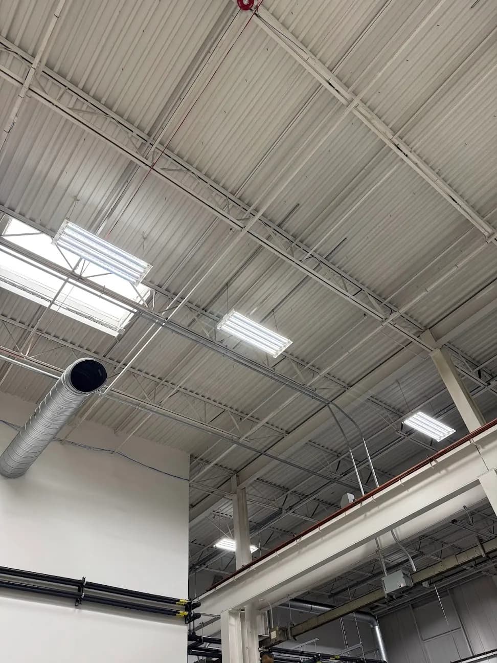 Ceiling lighting and conduit runs across an industrial ceiling structure