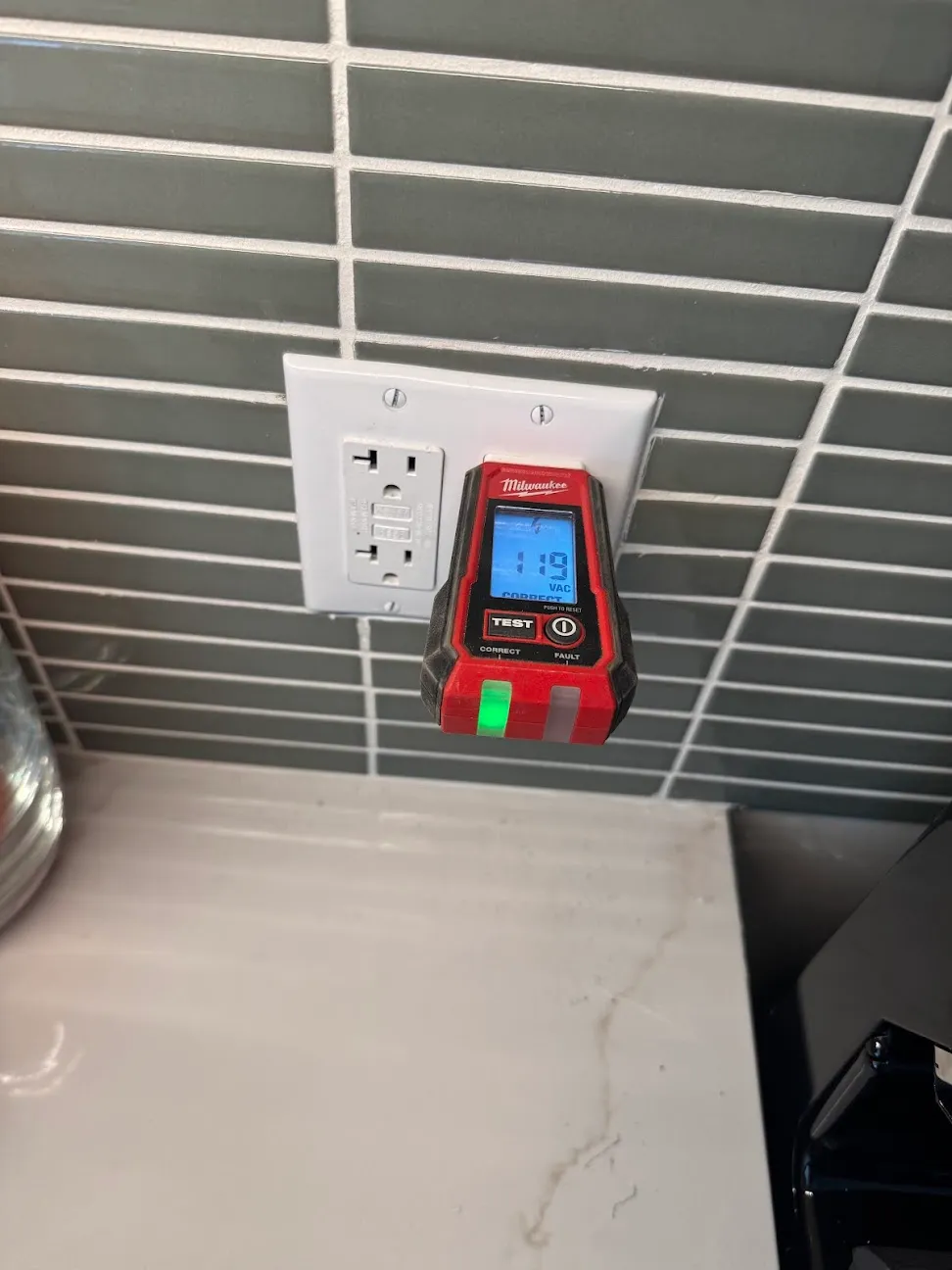 A plug-in circuit tester in a ceiling-mounted outlet showing a voltage reading